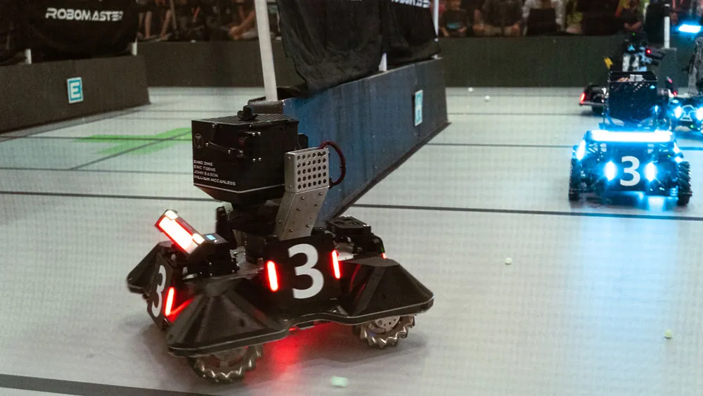 A red-lit robot in the foreground with a blue-lit robot behind it in the arena.